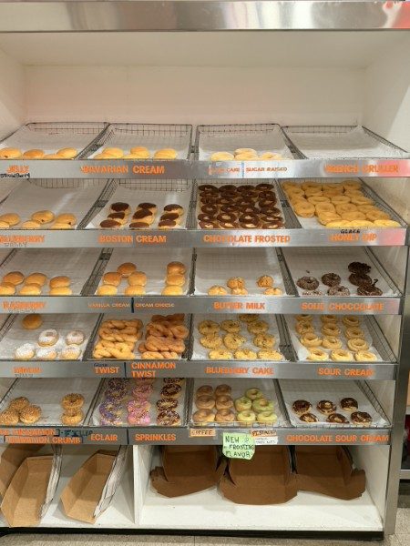 The donut display case stocked with Boston cream, fritters, twists, and more